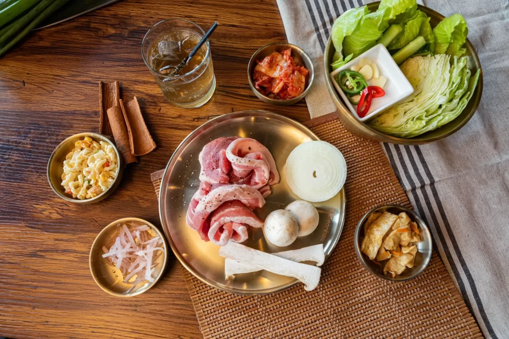 Korean BBQ pork belly with lettuce, kimchi, mushrooms, and side dishes at Geonbae Frankston VIC