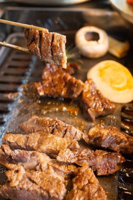 Grilled Korean BBQ beef being lifted from the grill at Geonbae Frankston VIC